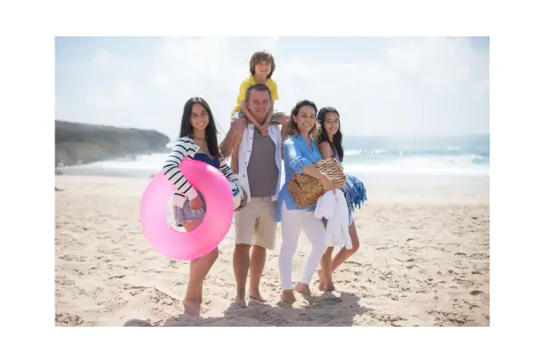 Família feliz com crianças pequenas aproveitando um dia ensolarado em uma praia durante uma viagem