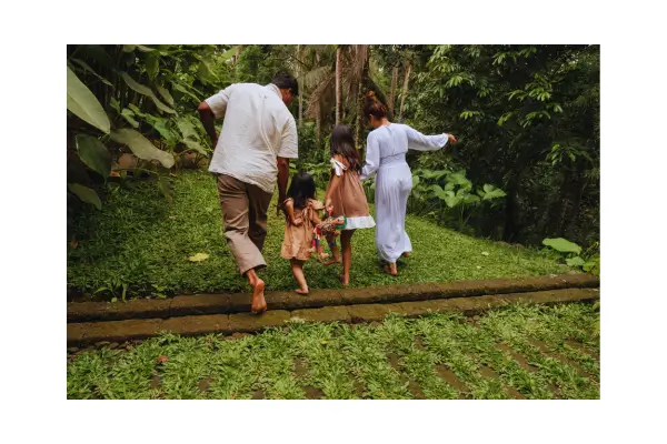 Família aproveitando um passeio ao ar livre em um hotel fazenda, cercada por natureza, com crianças interagindo com os pais desfrutando de um momento relaxante no campo