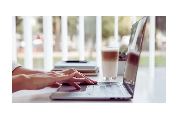 Pessoa trabalhando com notebook em um café moderno em Lisboa