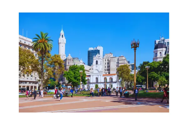 Vista panorâmica da Plaza de Mayo em Buenos Aires com a Casa Rosada e a bandeira argentina ao vento em dia ensolarado.